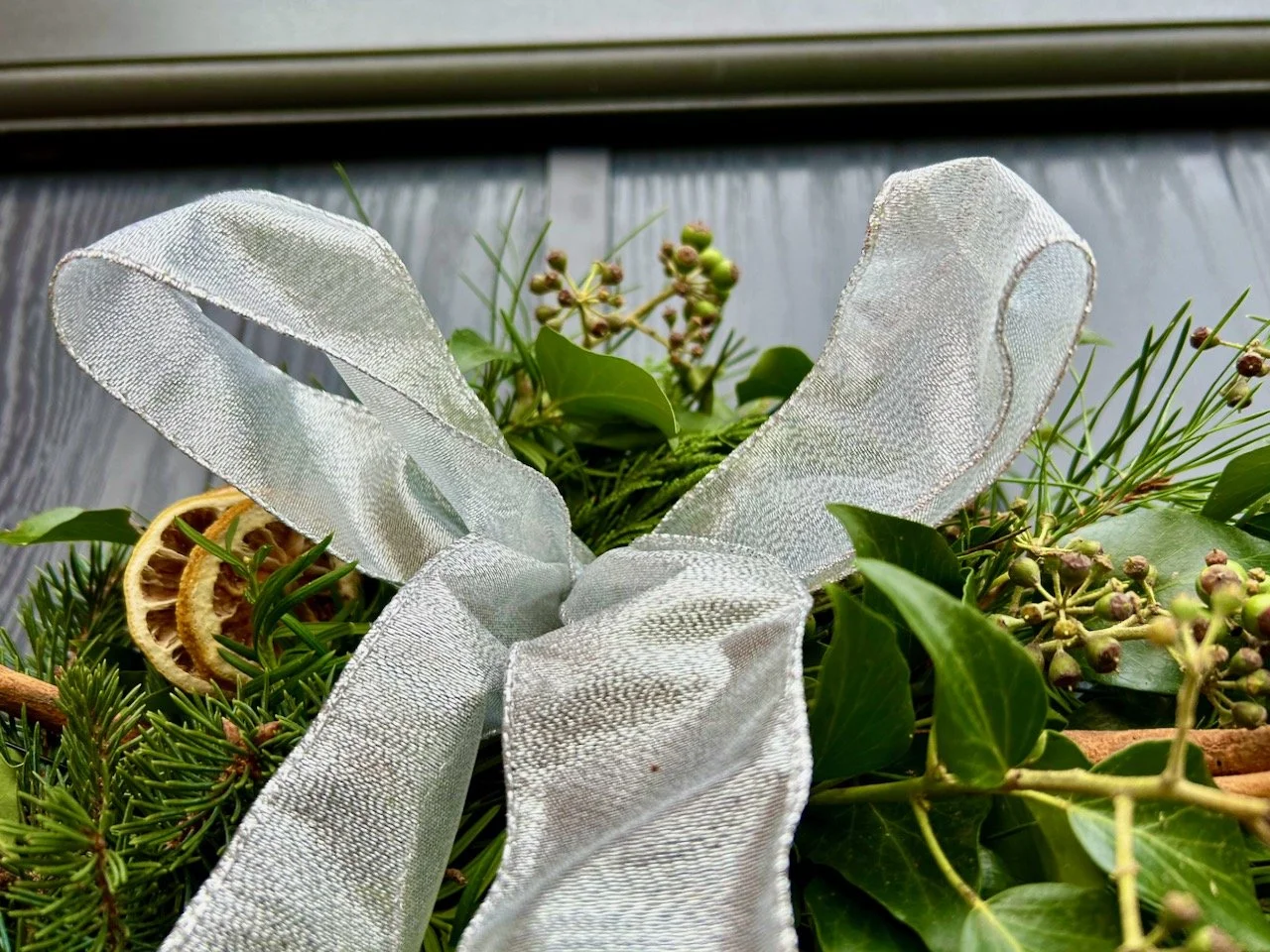 A closer look at the bow at the top of the wreath, the silver ribbon has wire in the edges and some transparency, the tails are long (to the bottom of the wreath) but aren't included in the photo