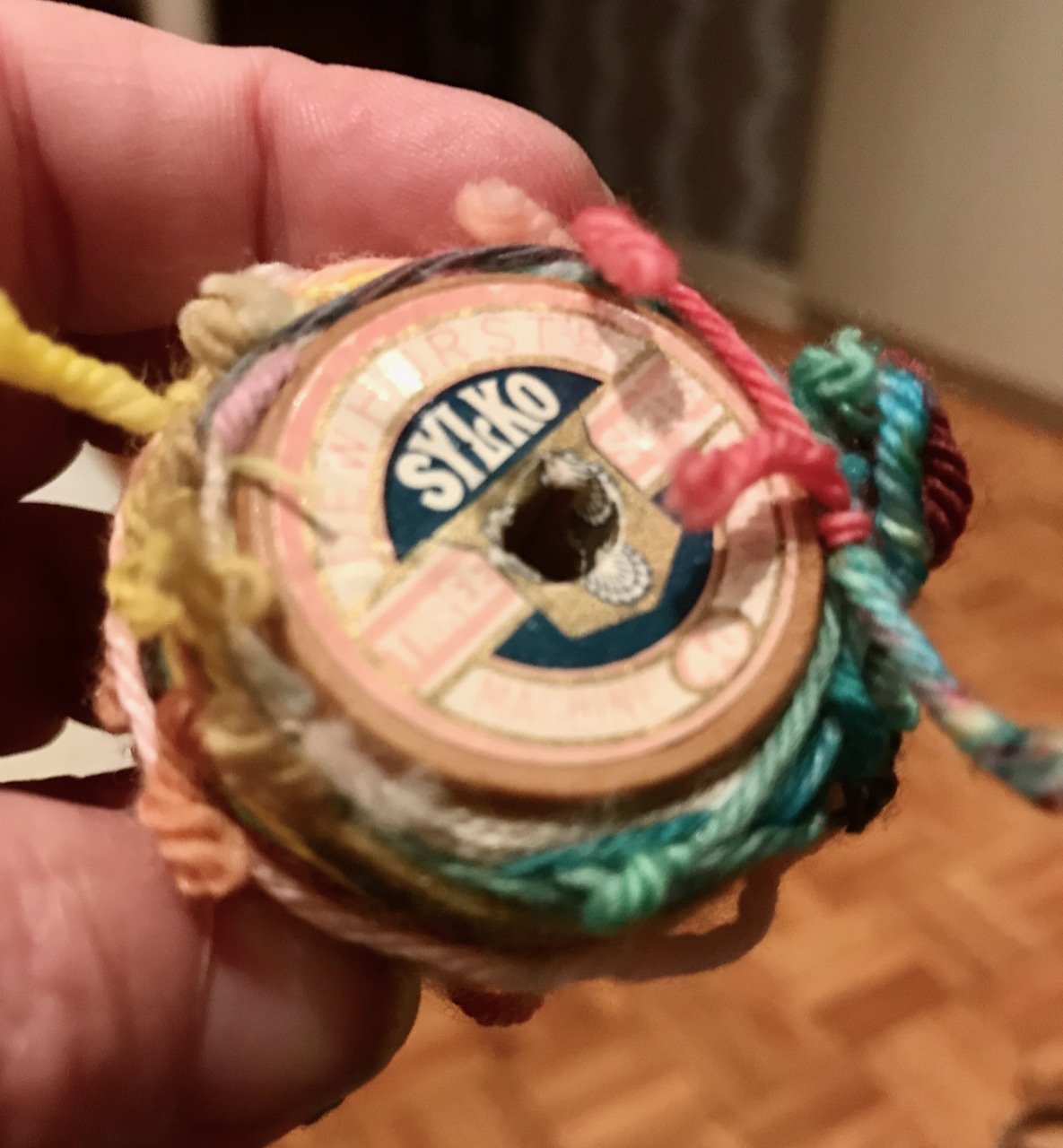 scraps of wool (used to tie skeins) wrapped around a wooden sylko cotton reel