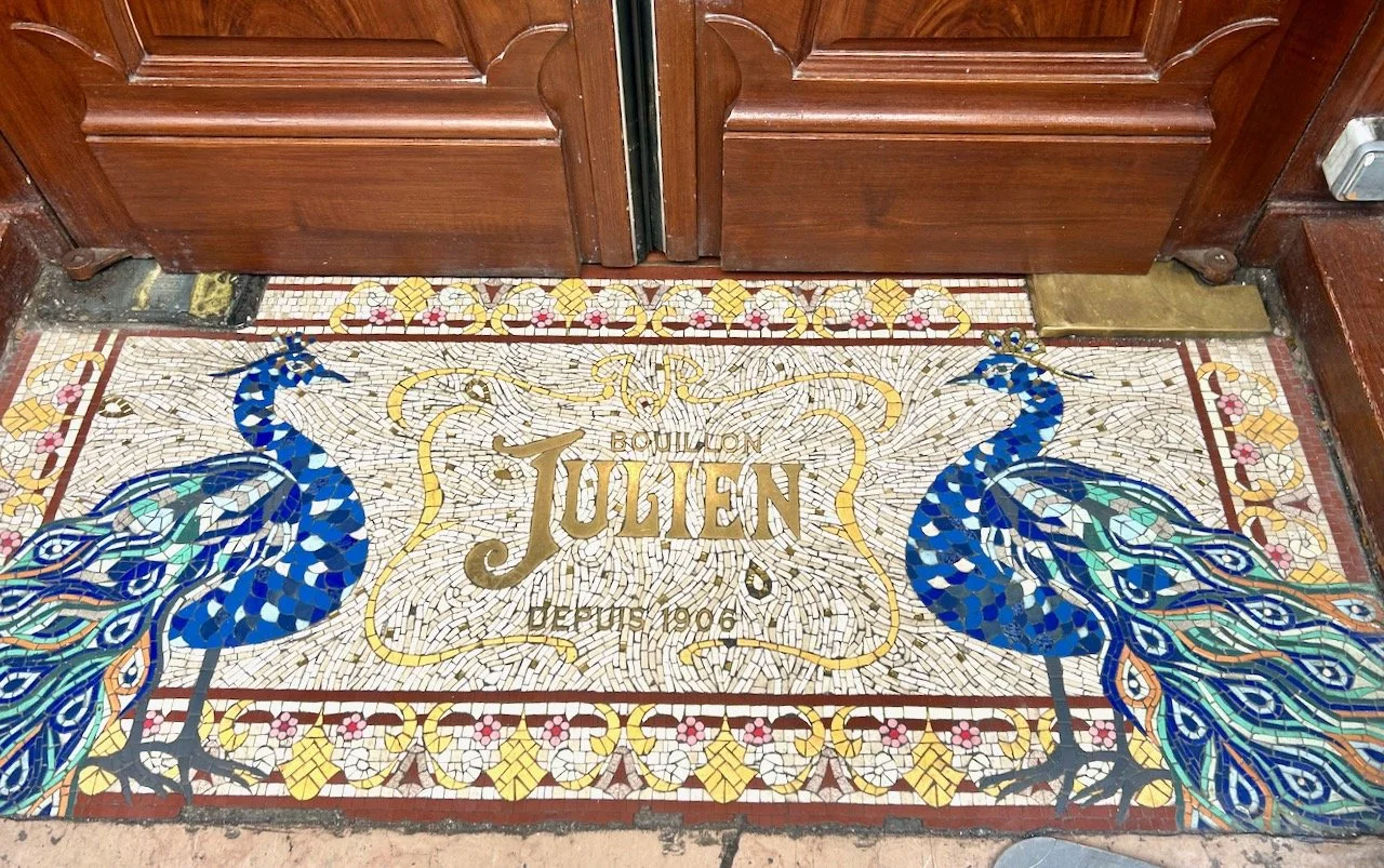 A mosaic on the doorstep of Bouillon Julien with two blue peacocks