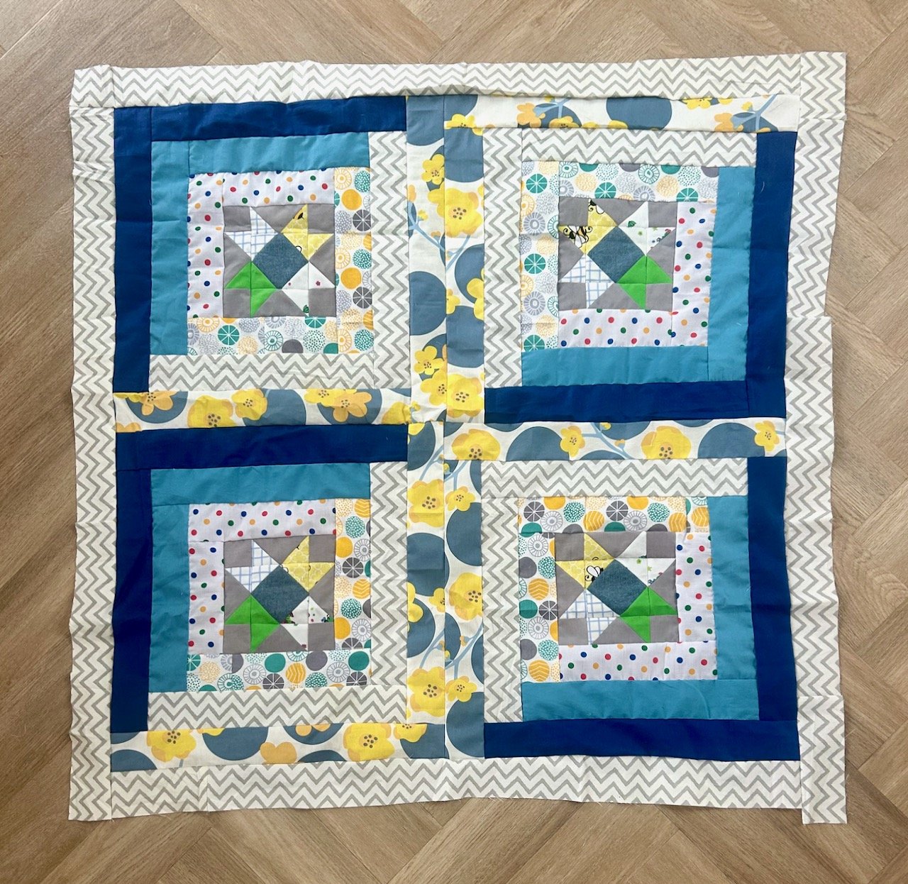 The four blocks are sewn together and a grey/white border has been added around the edge