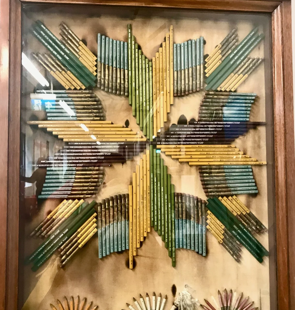 Green, yellow, grey and blue pencils laid out to form a star and framed