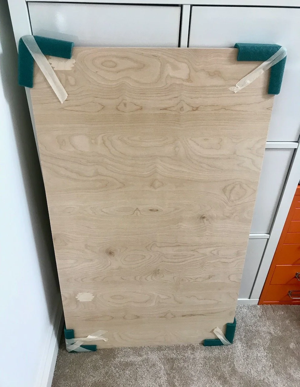 The plywood top of my desk standing in the corner of my craft room waiting for assembly