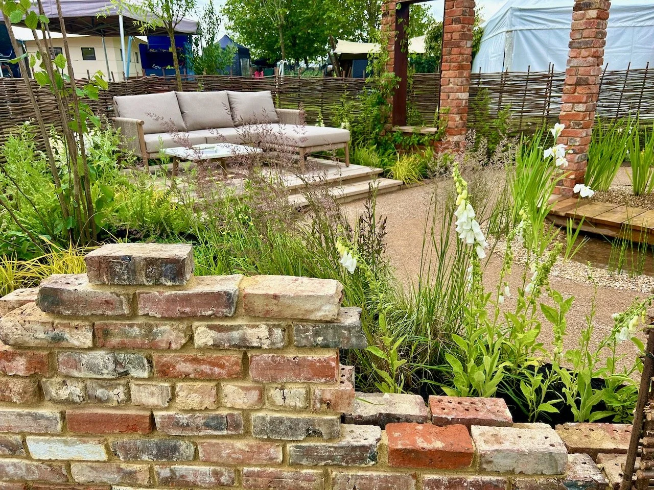 a part brick wall in the foreground, with a seating area in the background on a raised platform