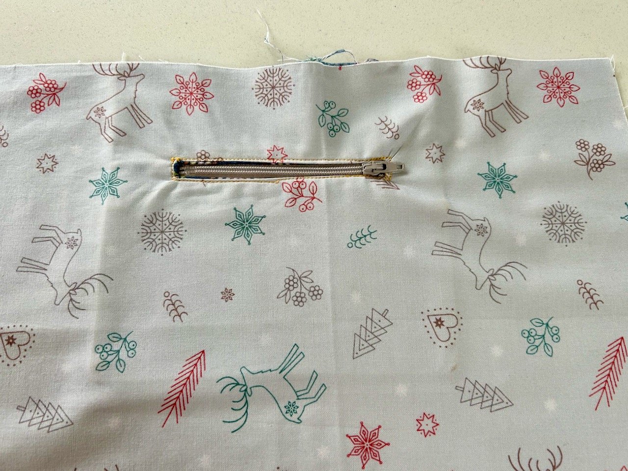 The grey christmas fabric with a beige zip and pocket inserted