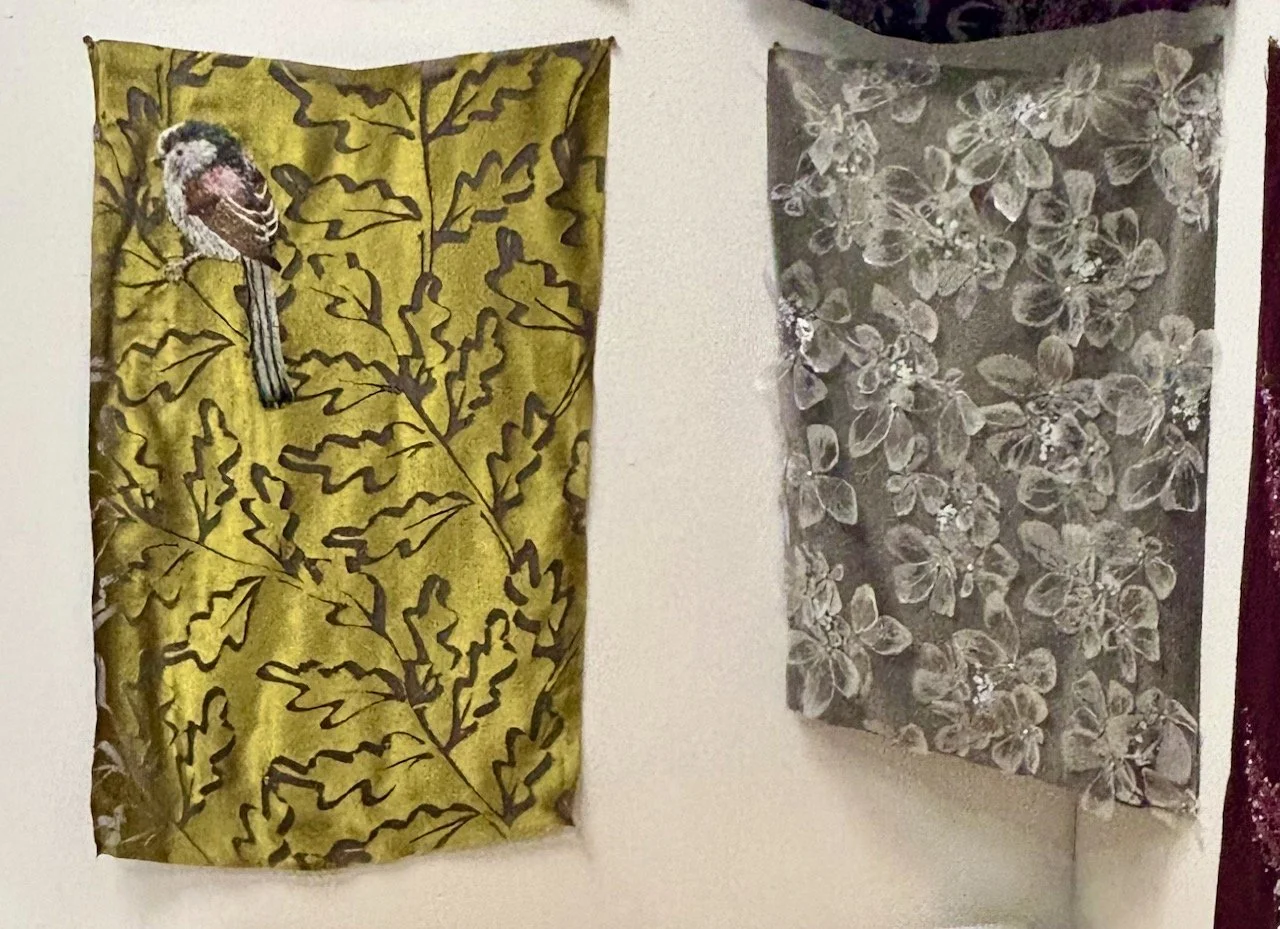 Two pieces hanging - on the left an embroidered bird on a gold textured background; on the right there's flowers which look like lace covering the whole panel
