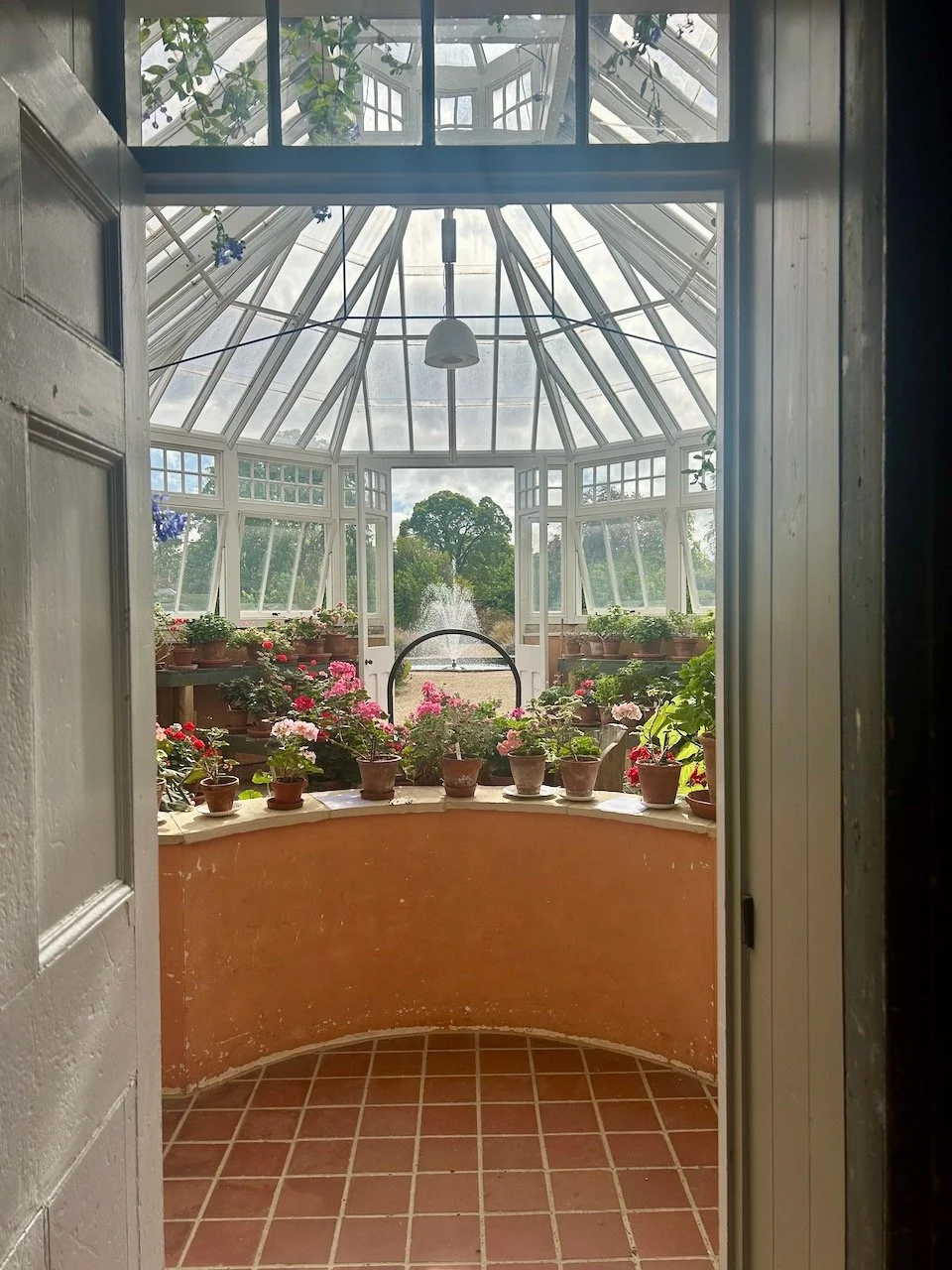 Looking back out of the conservatory towards the fountain with the geraniums in an arc at the bottom of the picture