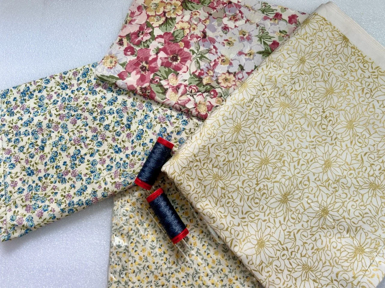 Four flowery patterned fabrics and two reels of thread
