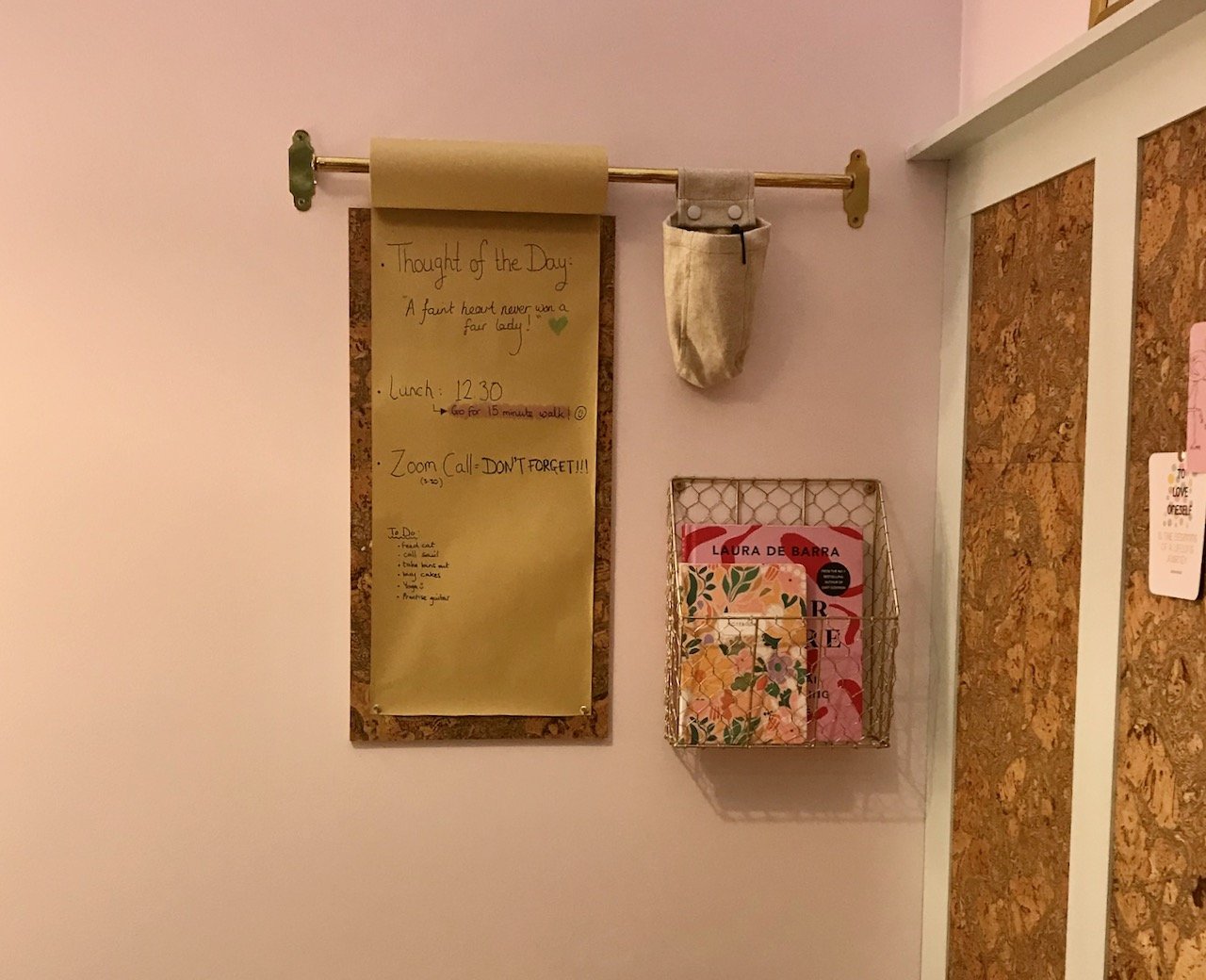 Focusing on the noticeboard - a rail for a roll of paper whichis pinned  onto two cork tiles, with a mesh brass magazine rack alongside
