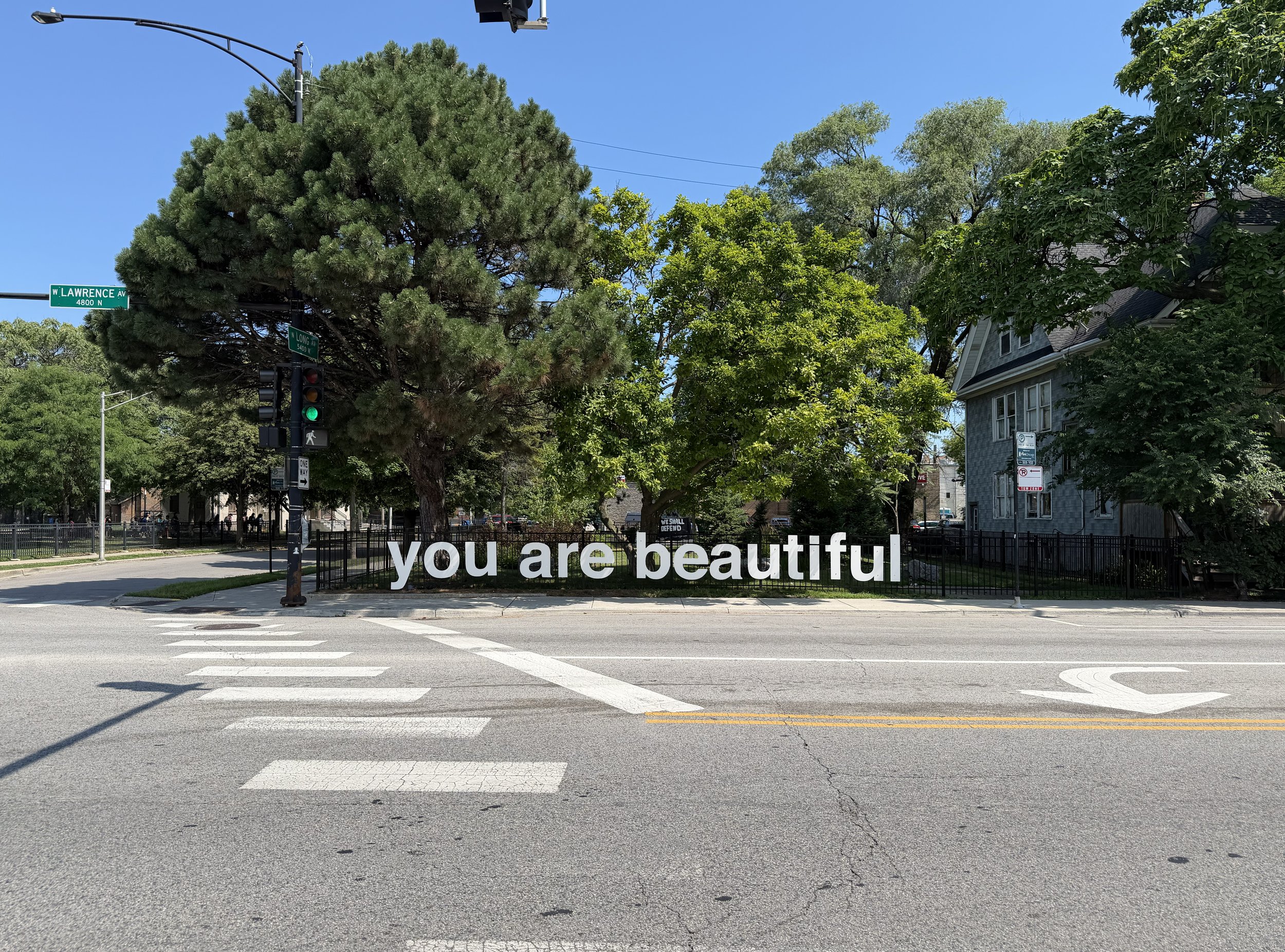 Large grey "you are beautiful" public art sculpture installed in the Jefferson Park Sculpture Garden at Lawrence and Long in Chicago.
