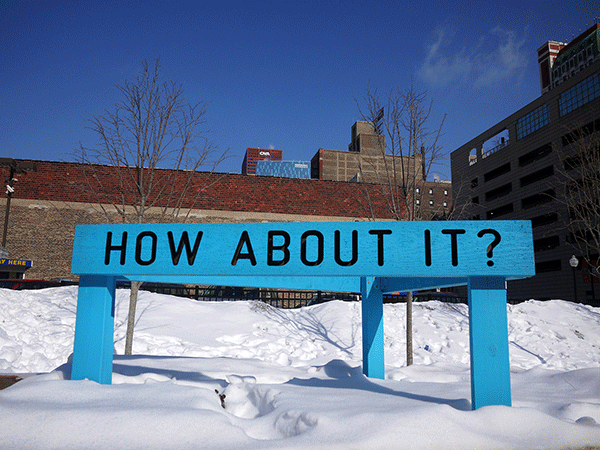 “Being Human Equals Hope” outdoor installation by Matthew Hoffman, yellow frame structure in snowy Chicago park with high-rise buildings.