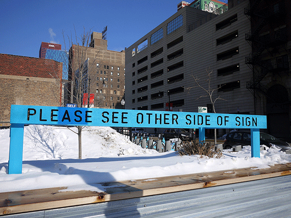 “Being Human Equals Hope” outdoor installation by Matthew Hoffman, yellow frame structure in snowy Chicago park with high-rise buildings.