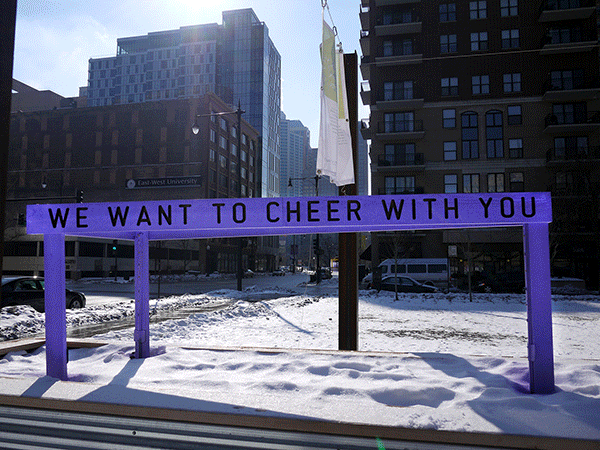 “Being Human Equals Hope” outdoor installation by Matthew Hoffman, yellow frame structure in snowy Chicago park with high-rise buildings.