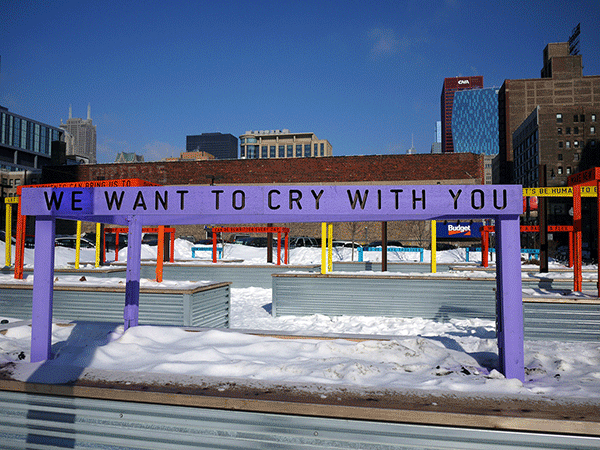“Being Human Equals Hope” outdoor installation by Matthew Hoffman, yellow frame structure in snowy Chicago park with high-rise buildings.