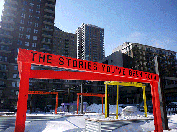 “Being Human Equals Hope” outdoor installation by Matthew Hoffman, yellow frame structure in snowy Chicago park with high-rise buildings.