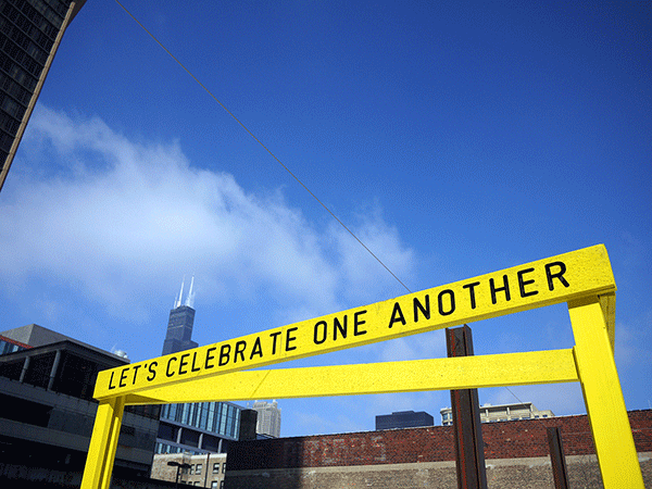 “Being Human Equals Hope” outdoor installation by Matthew Hoffman, yellow frame structure in snowy Chicago park with high-rise buildings.