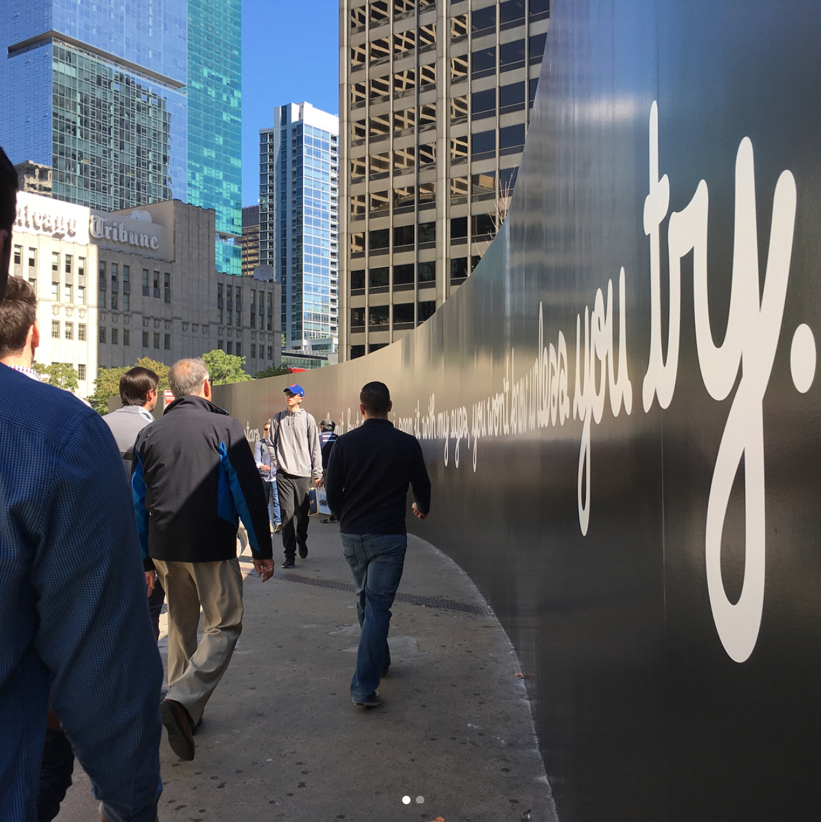 Chicago city sidewalk with large “Where Ideas Sing” wall mural by Matthew Hoffman on Apple Michigan Avenue store.