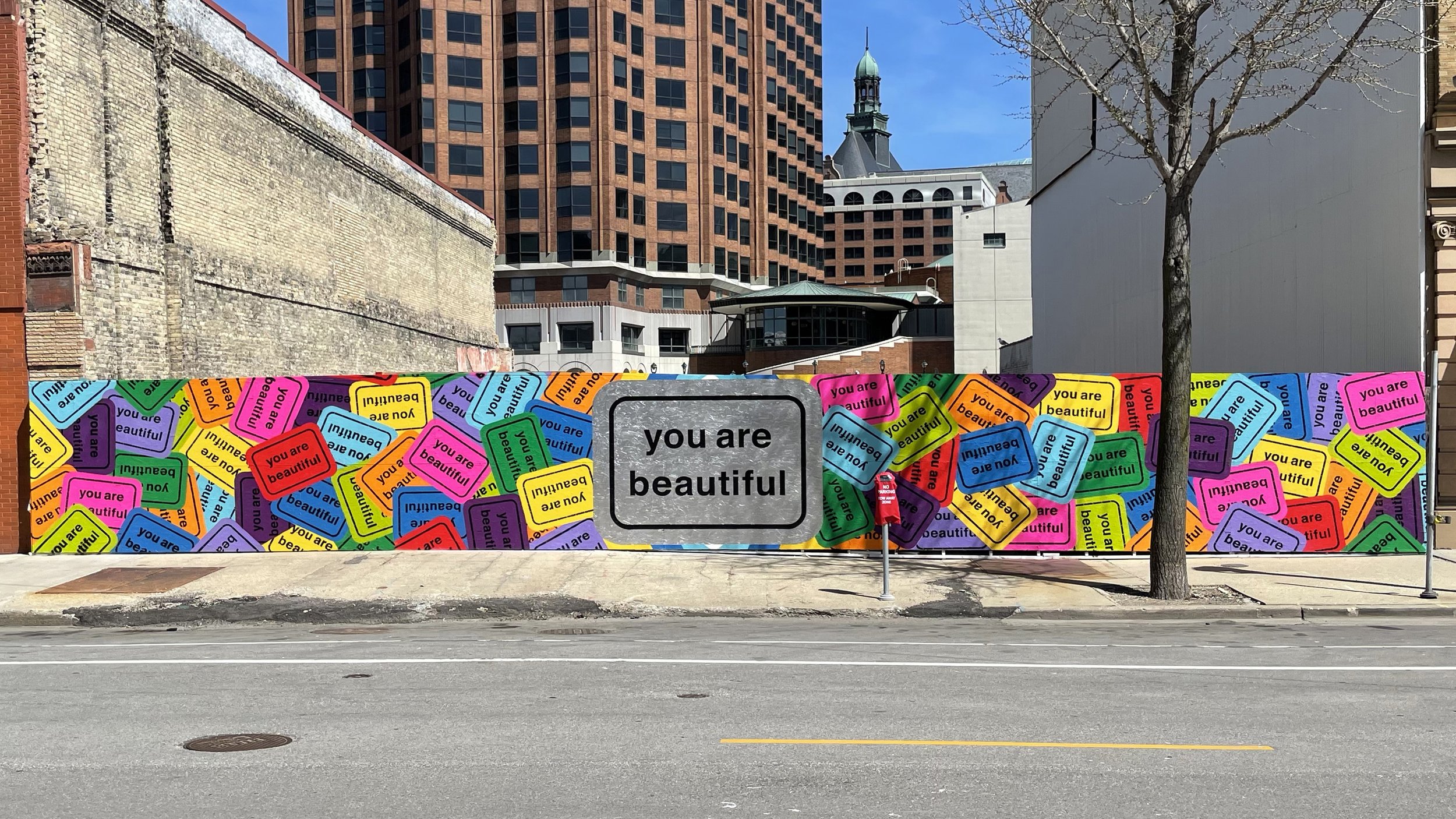 Large You Are Beautiful collage mural covering a temporary construction wall in downtown Milwaukee, Wisconsin.