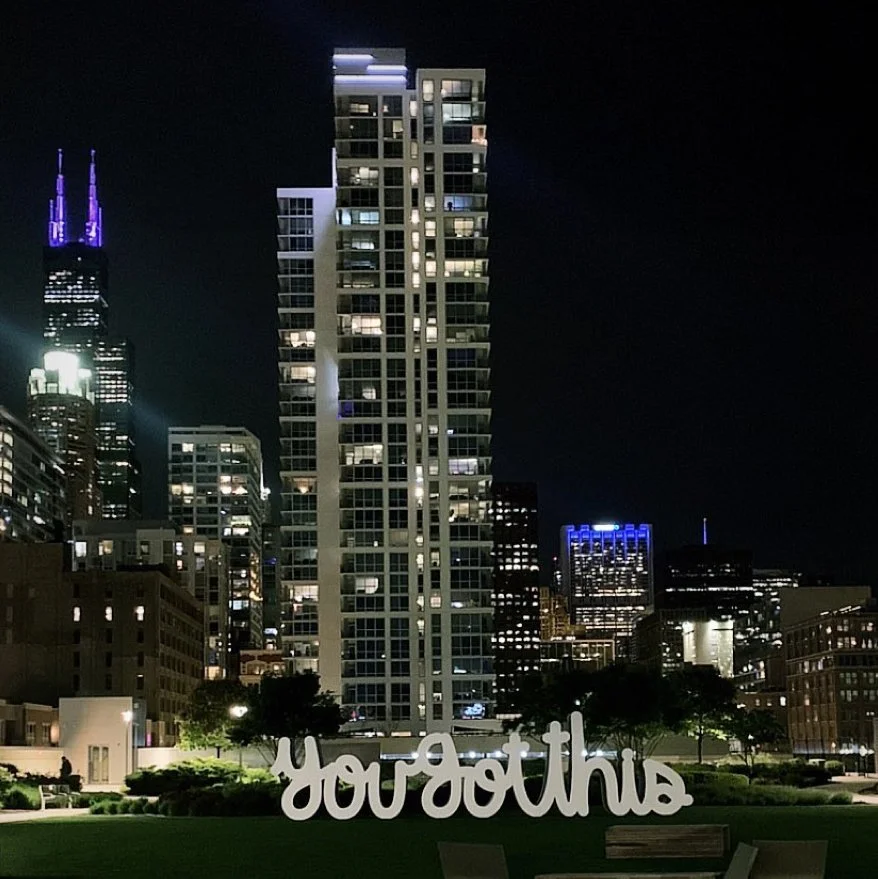 Large-scale “You Got This” public art sculpture by Matthew Hoffman installed in downtown Chicago with surrounding urban architecture and skyline views.