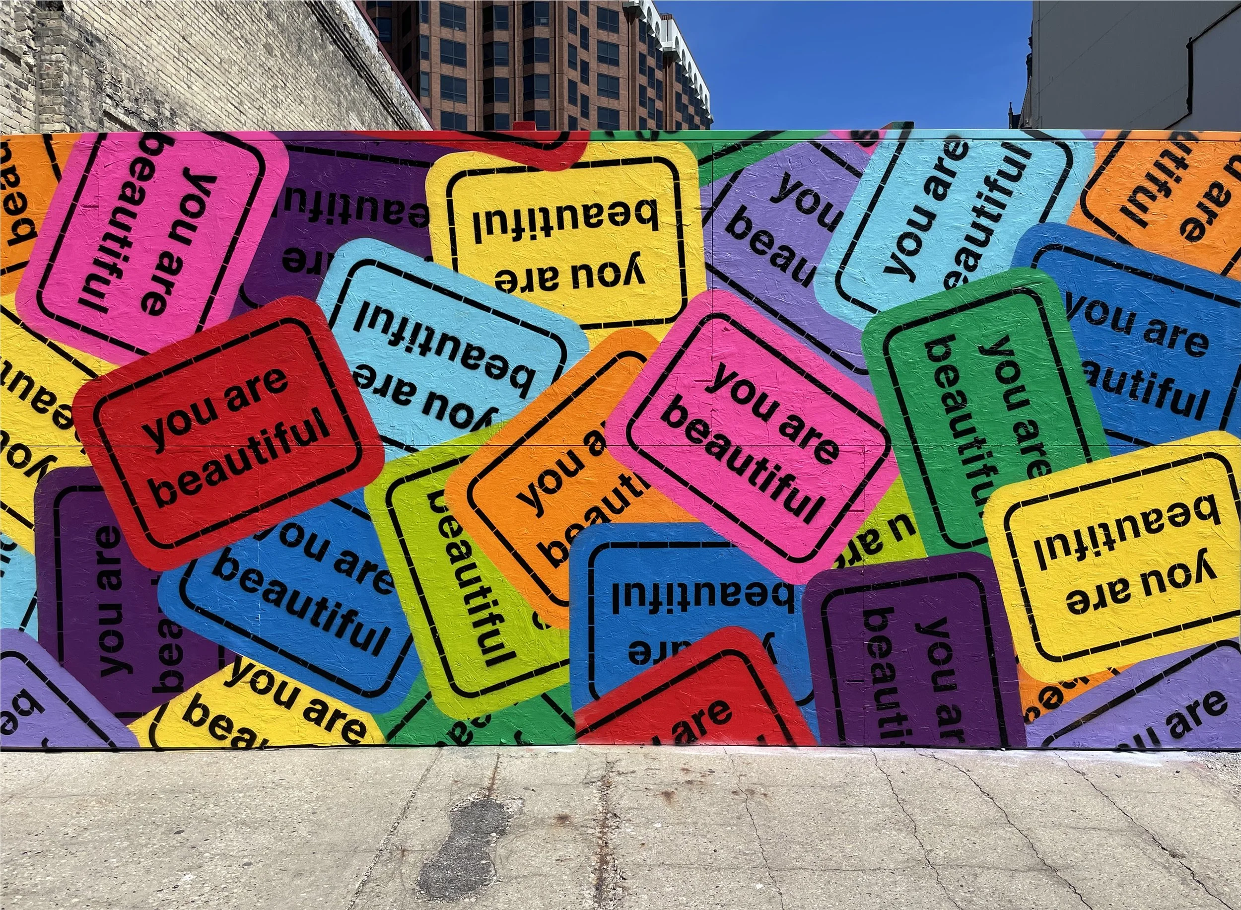 Large You Are Beautiful collage mural covering a temporary construction wall in downtown Milwaukee, Wisconsin.