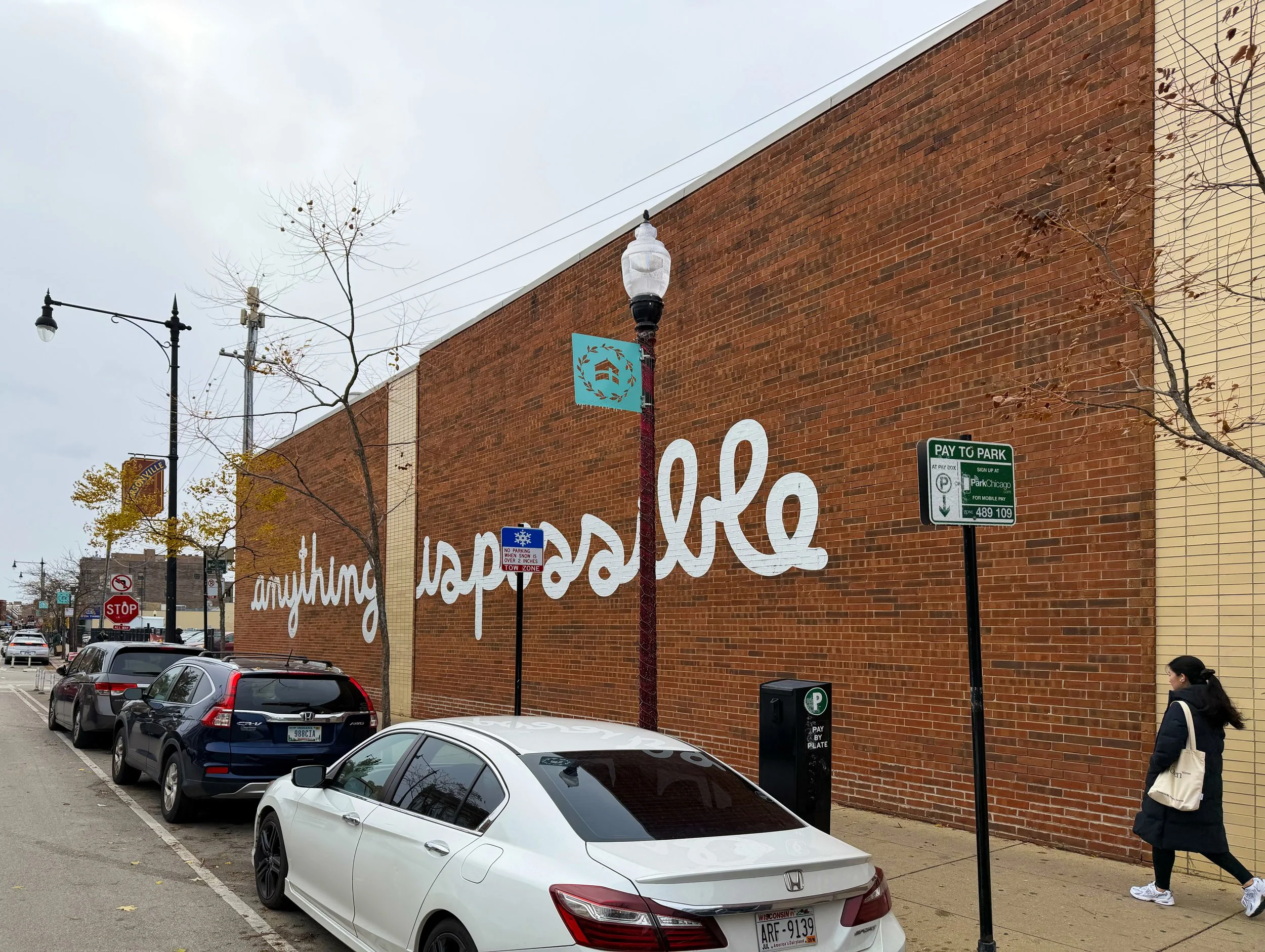 Anything Is Possible mural by Matthew Hoffman stretching across a long brick wall in Chicago's Andersonville neighborhood during winter beneath an overcast sky.