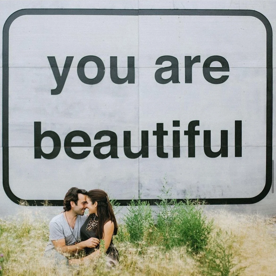 Visitors photographing Matthew Hoffman’s “You Are Beautiful” sign along Lake Shore Drive, a Chicago landmark celebrating self-worth.