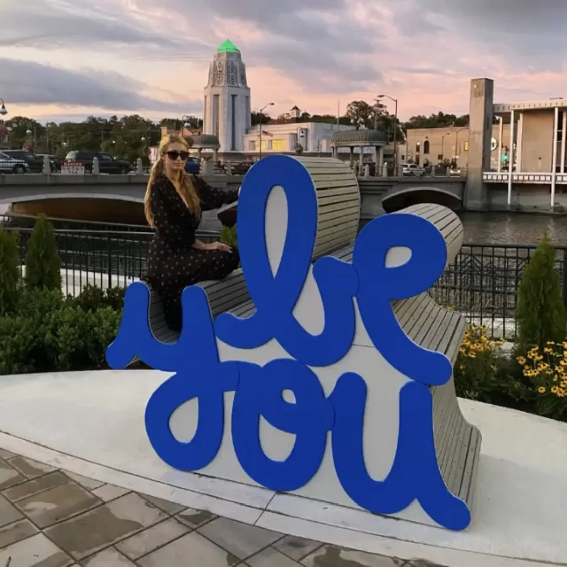 Paris Hilton posing with Matthew Hoffman’s “Be You” public art sculpture in St. Charles, a joyful landmark celebrating self-expression.