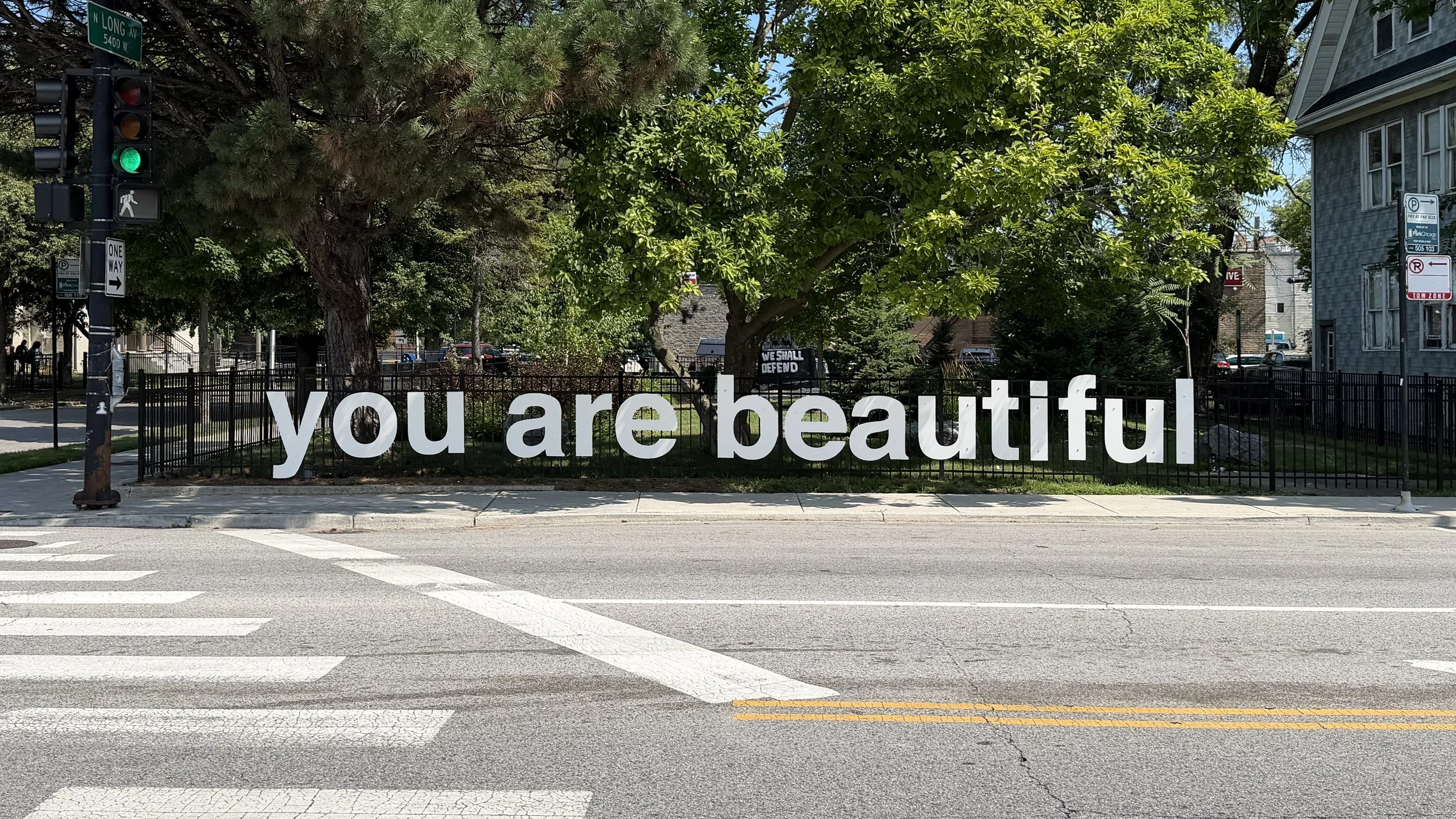 Large grey "you are beautiful" public art sculpture installed in the Jefferson Park Sculpture Garden at Lawrence and Long in Chicago.