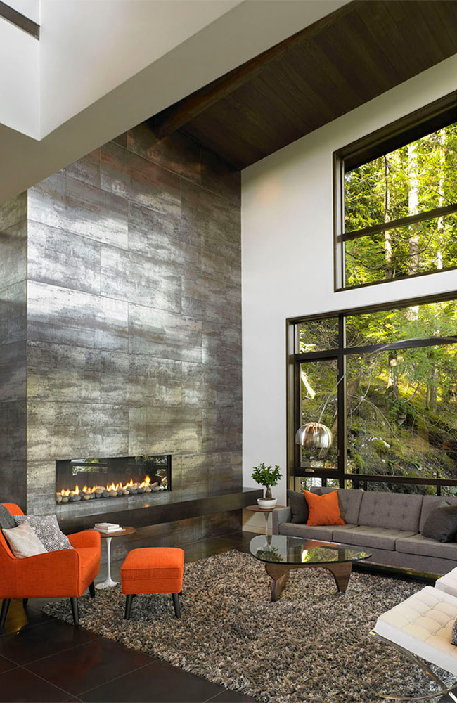  White wall and metallic floor and fireplace surfaces are essentially colorless. By contrast, the verdant hues of nature take center stage. Metaphorically speaking, the message is that human made materials are subordinate to works of nature.     