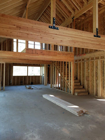 Laminated girders stand free in the lofty great room and support the master suite above the kitchen and dining area