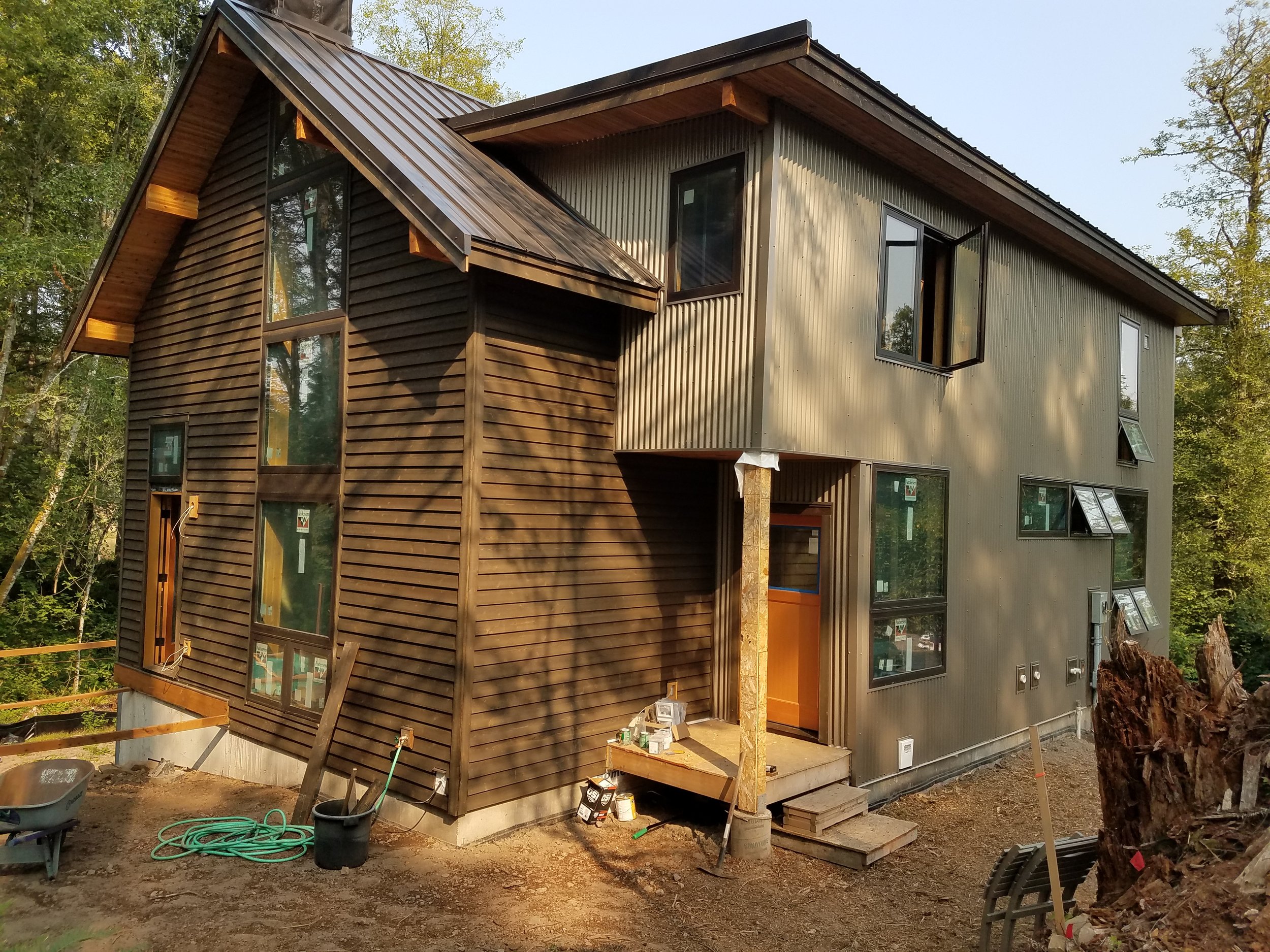 The entry dormer, clad in corrugated steel,  contrasted against the cedar siding, overhangs, and lam beams of the main house form