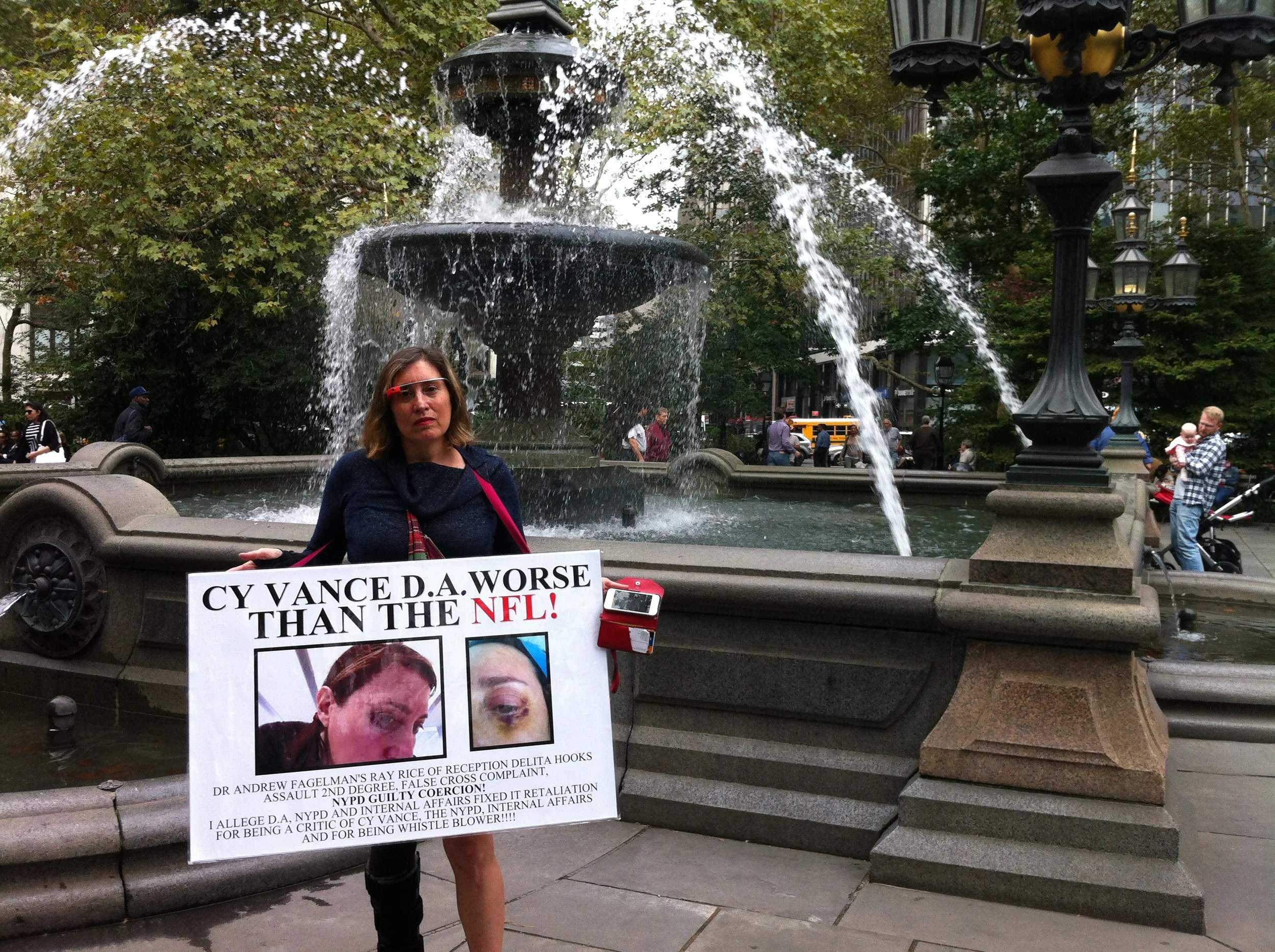 The artist and political blogger Suzannah B. Troy stood near the fountain at City Hall Park with her protest sign. Activists distributed cards and flyers with information about the upcoming NYPD Five Points March for Reform. Source : Louis Flores