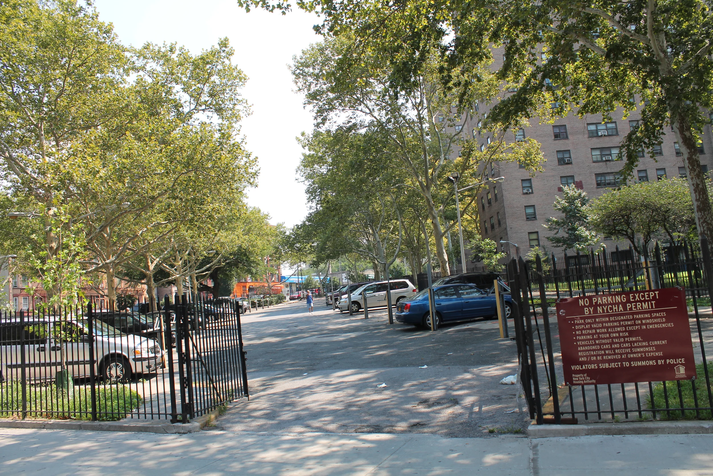 A gated parking lot at the Mill Brook Houses in Mott Haven, The Bronx, as seen on Monday, August 17, 2015. New York City Housing Authority CEO Shola Olatoye has said that spaces identified for its controversial infill plan to lease open lots on NYCHA properties to private real estate developers can be rationalised, because the proposed sites are "strewn with trash" and not in use. However, the condition of the Mill Brook Houses parking lot was relatively well kept, except for discards that are typically wind-blown from city sidewalks. Source : Louis Flores/Progress Queens