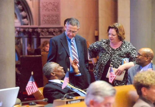 New York State Assemblymember Keith Wright (D-Harlem), seated at left, with left-to right : Former Speaker Sheldon Silver (D-Lower East Side), Assemblymember Catherine Nolan (D-Woodside), and former Assemblymember Darryl Towns (D-East New York) in an undated photograph. Since this photograph was taken, former Assemblymember Silver has been convicted of Federal corruption charges, and former Assemblymember Towns was appointed CEO of the New York State Homes and Community Renewal . Source : New York State Assembly/Public Domain