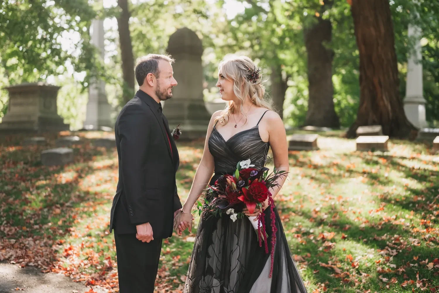 A Halloween wedding couple celebrates their wedding and is taking pictures in the Forrest Home Cemetery. The bride is wearing a beautiful black wedding dress!
