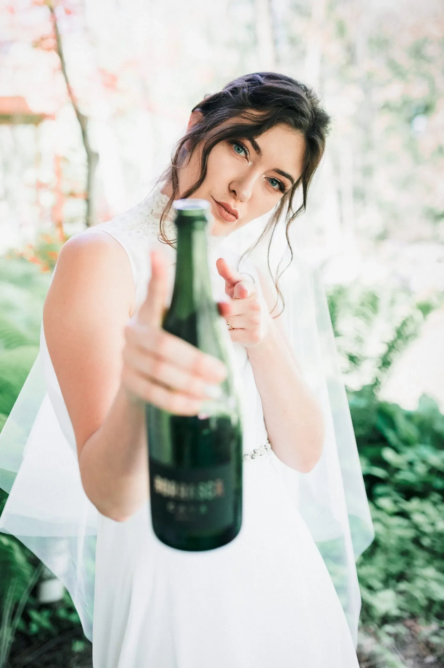 Bride Holds her bottle of Champagne and points at the camera | Milwaukee Wedding Photographer | Roost