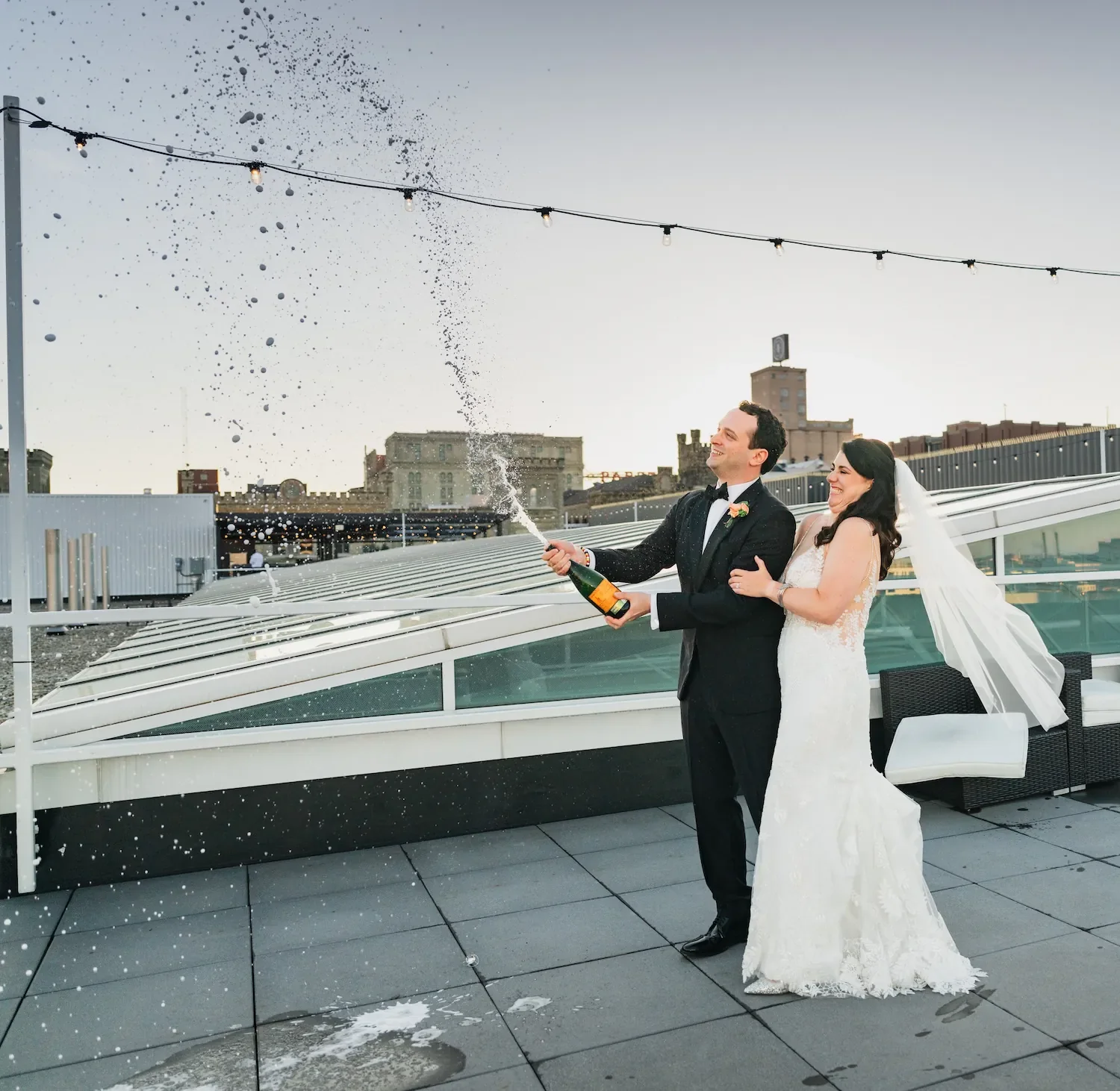 bride and groom pop chapmagne pop on the Pilot Project Rooftop in the brewery district milwaukee wisconsin.webp