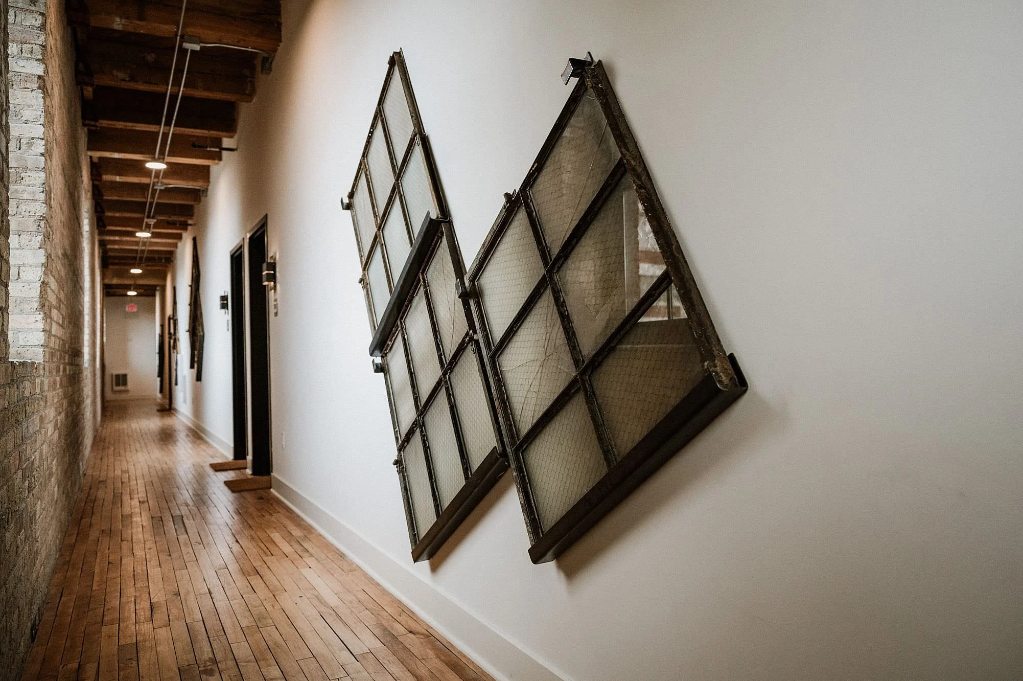 A view down a renovated hallway that has used windows from the orignal warehouse as wall accents to capture their history