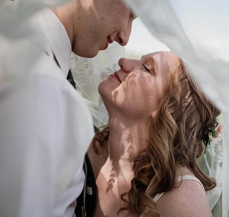A close-up of a bride and groom sharing an intimate moment during their wedding, with faces close together and soft lighting.
