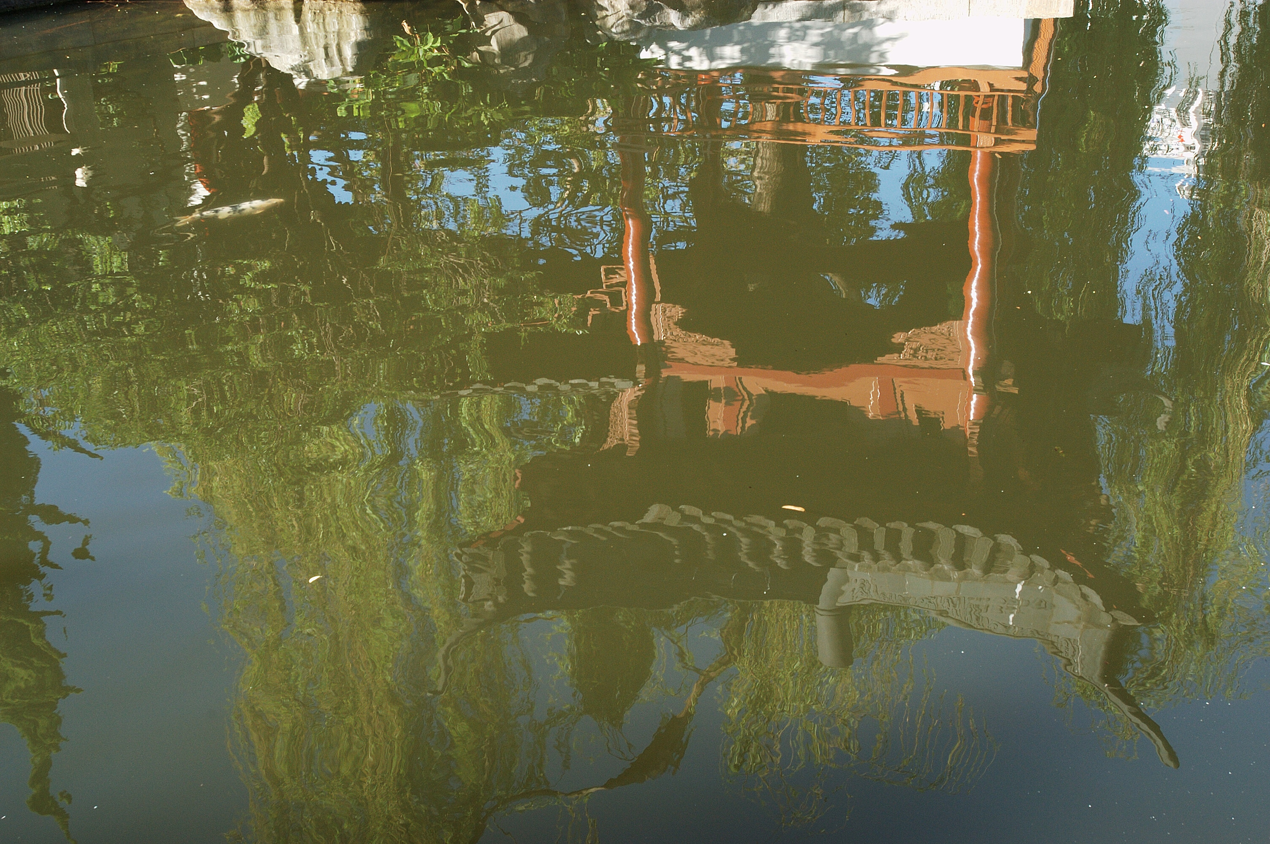 The reflection of a pagoda structure in a pond in the garden