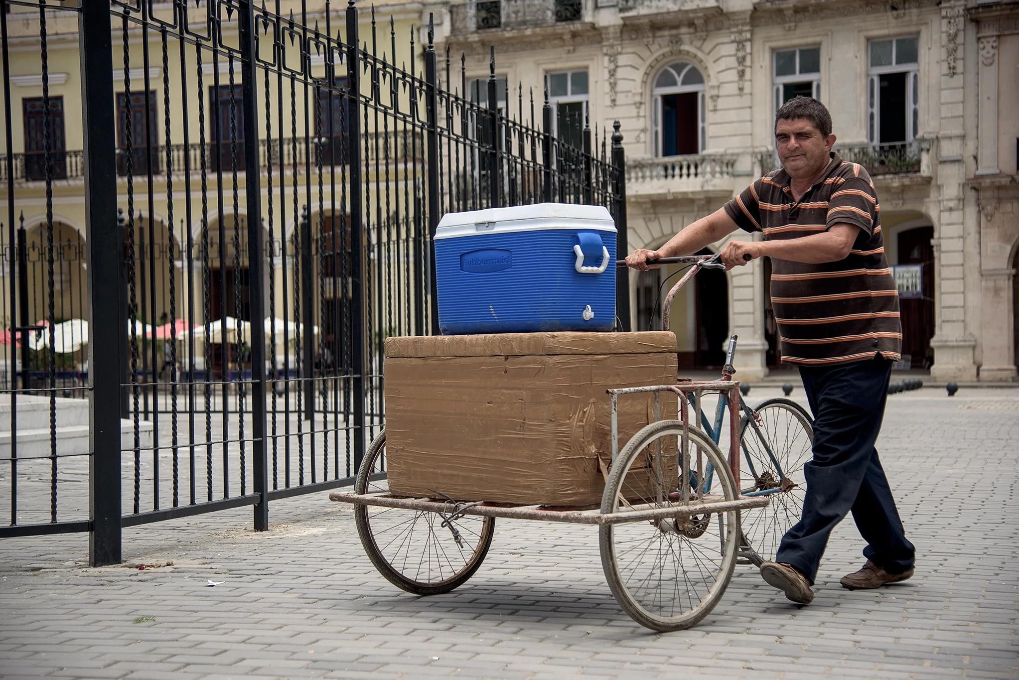 A man makes deliveries for work, and sells water to tourists from a blue cooler, likely it came into Cuba with relatives on charters from Miami. We saw everything from bike tires to hula hoops and baby strollers on the baggage claim in Havana on our Miami charter. 
