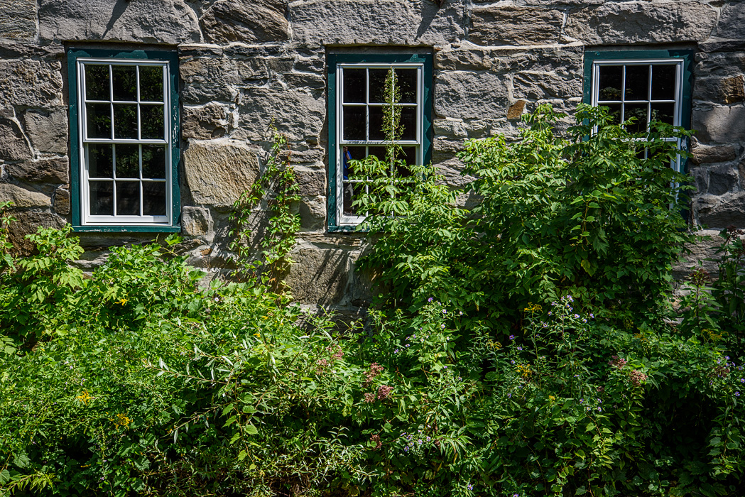 Alongside Central Street. a tiny pocket park by the Kedron Brook sits in the shadow of an old stone building.