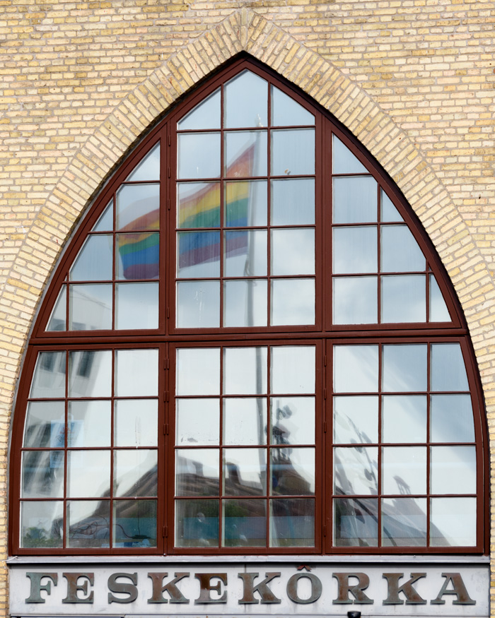 A window of the Feskekorka reflects a nearby pride flag on pride weekend. 