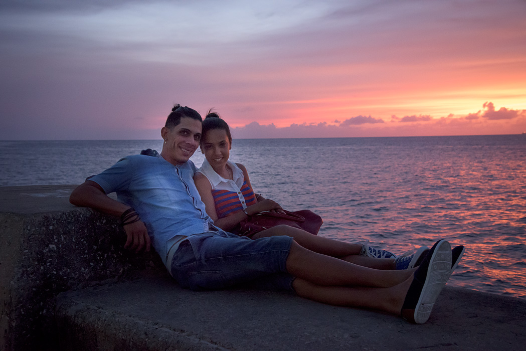 A young couple enjoys the sunset on the malecon in Havana