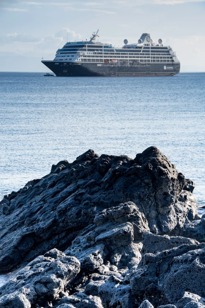 Azamara Quest at anchor near the lava rock coast of Sicily.