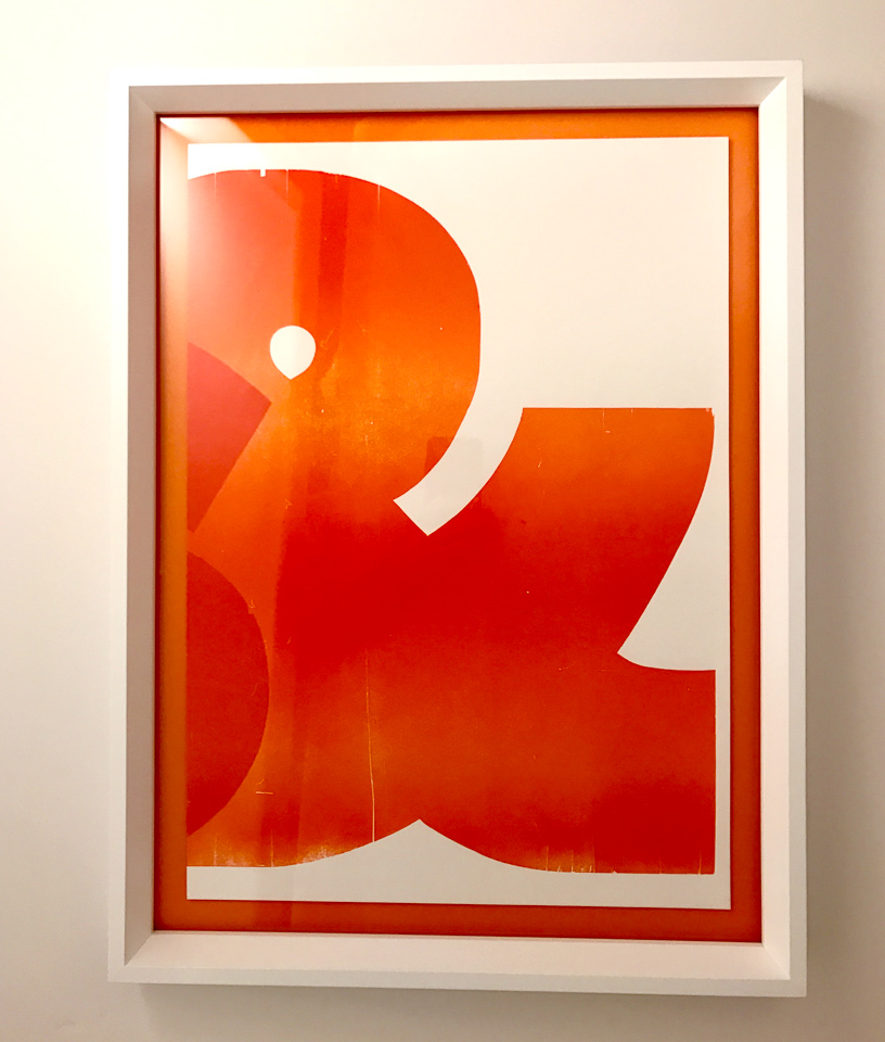 Graphic ampersand floated on orange and framed in white.