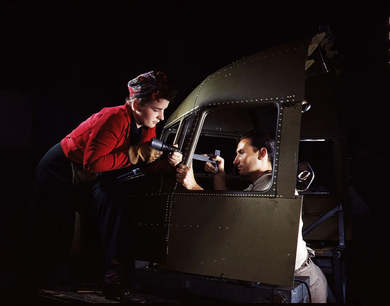A man and woman riveting team working on the cockpit shell of a C-47 aircraft at the plant of North American Aviation (1942). Photographer: Alfred T. Palmer
