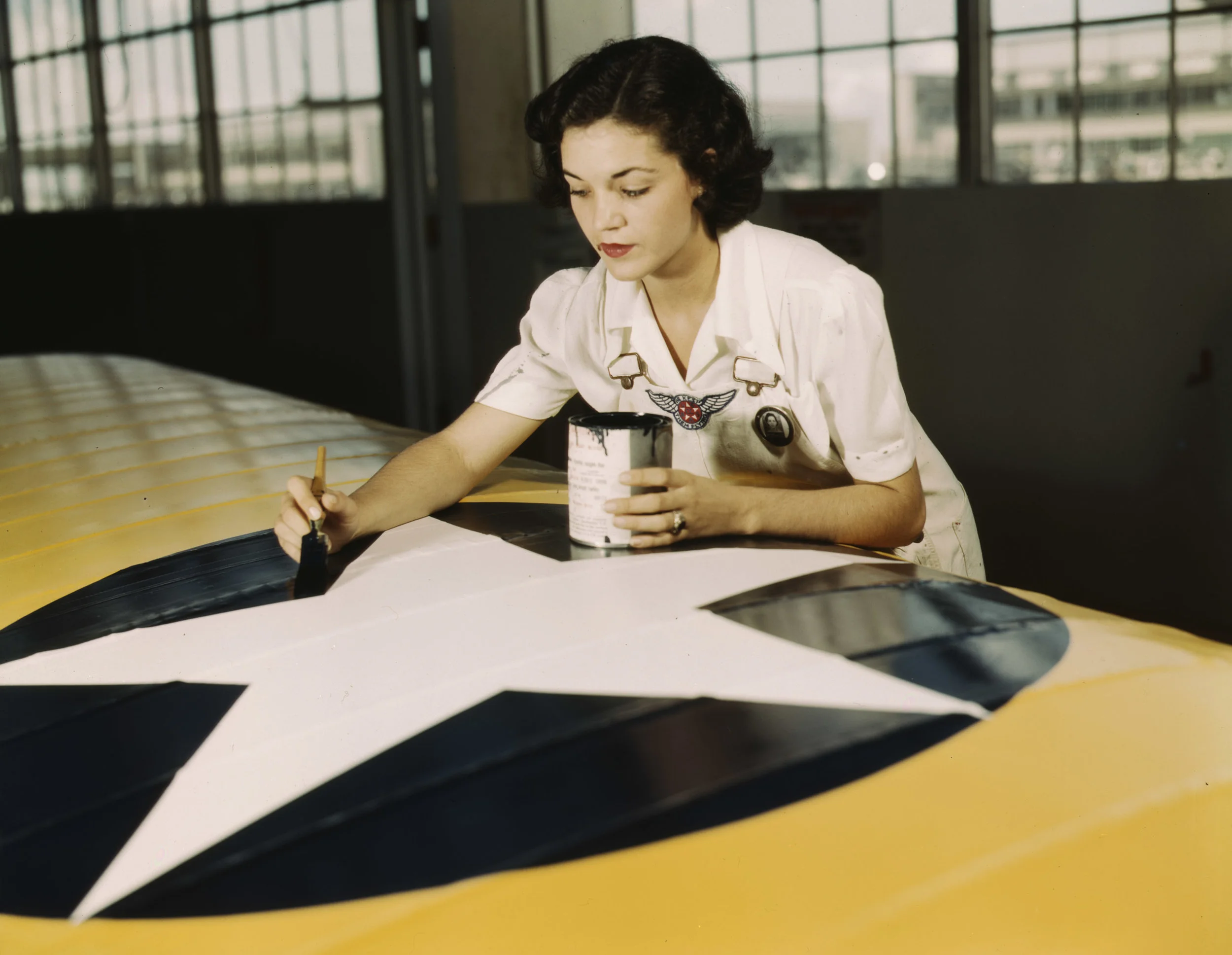 Mrs Irma Lee McElroy painting the American insignia on airplane wings at Naval Airbase, Corpus Christi, Texas. Photographer: Howard R. Hollem