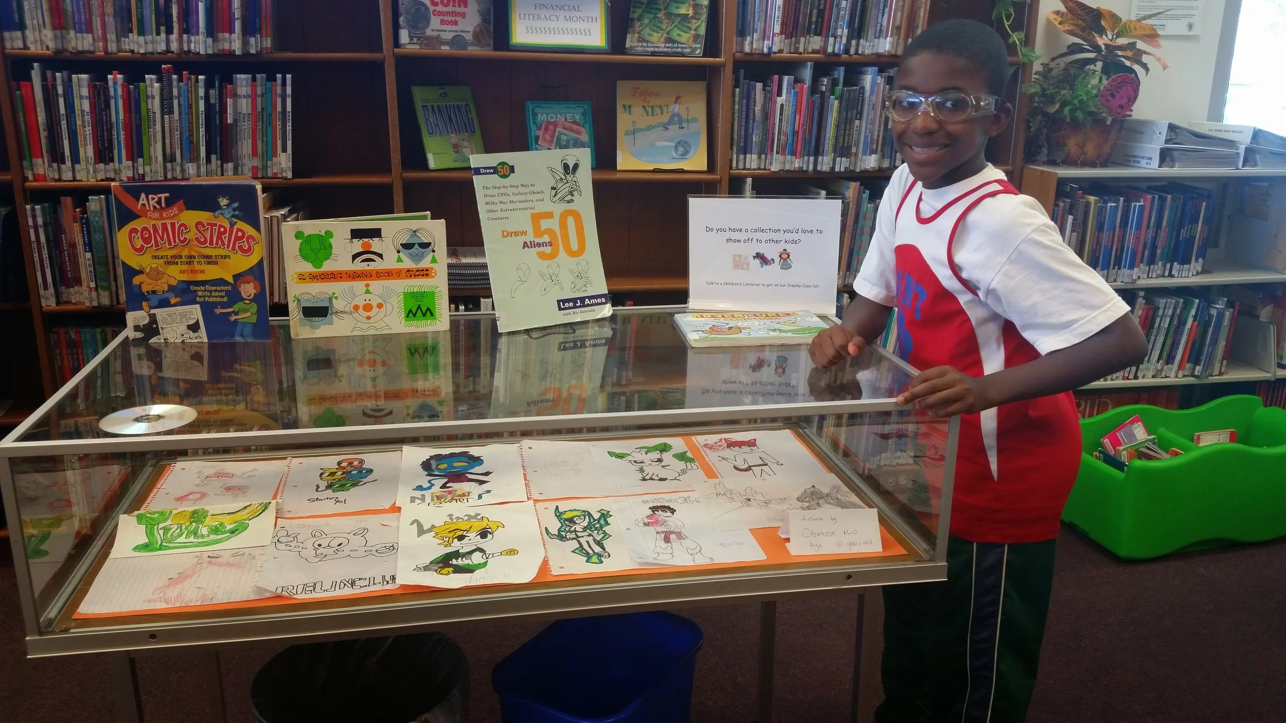 Chigozie next to his artwork. The 11 year old recentlyhad a display at the White Oak Branch of the Silver Spring Library. 