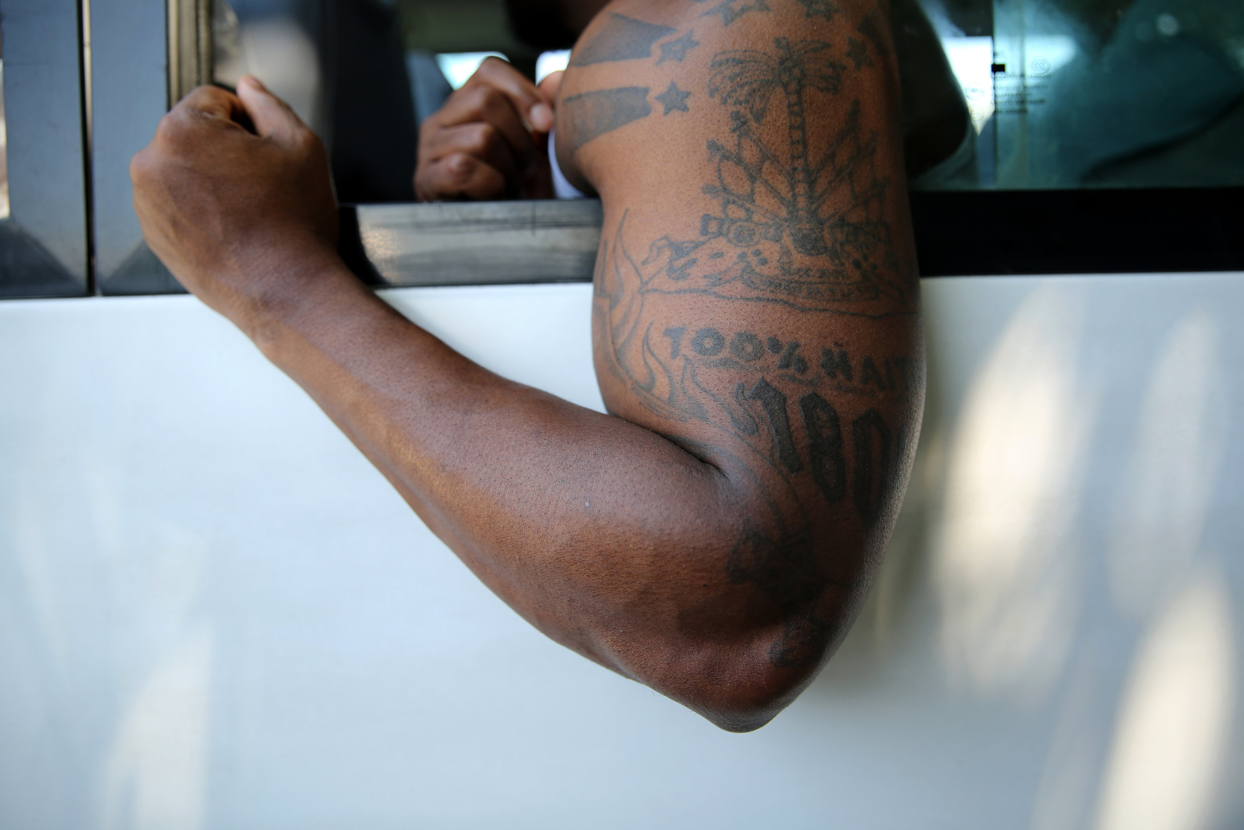   Stevens Arnoux on a bus of Haitian-American deportees arriving at the Toussaint Louverture International Airport in Port-au-Prince in March 2014. He displays his tattoo, which says “100% Haitian 1804.”  