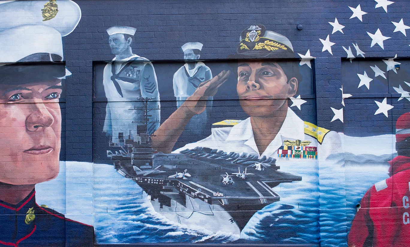 A close up of the Admiral Michelle Howard alongside an aircraft carrier.